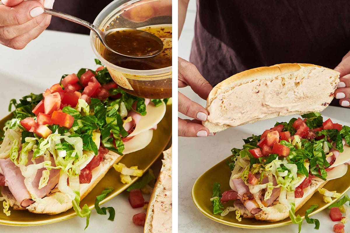 Woman spooning dressing onto a Sandwich filled with veggies, meats, and cheeses.