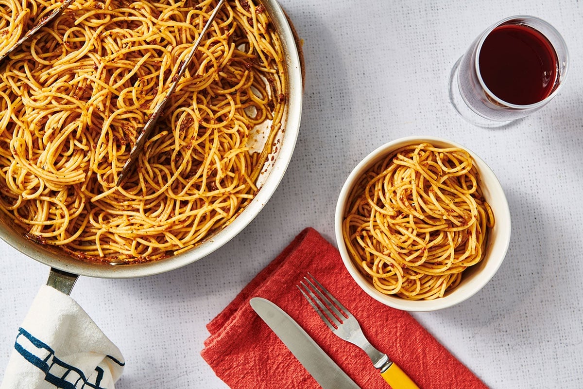 Spaghetti with sun-dried tomato pesto in bowls on table.