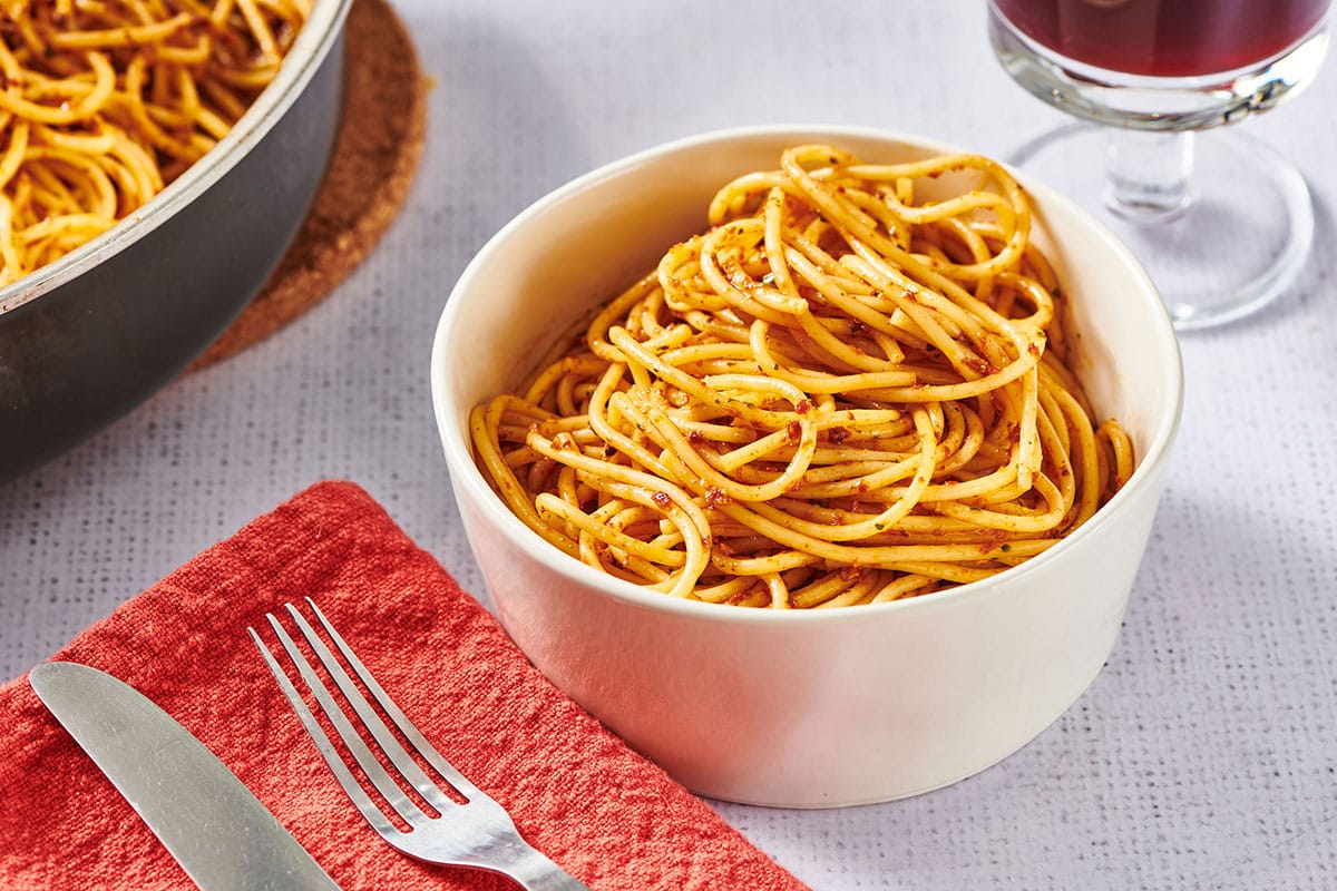 White bowl of sun-dried tomato pesto with spaghetti