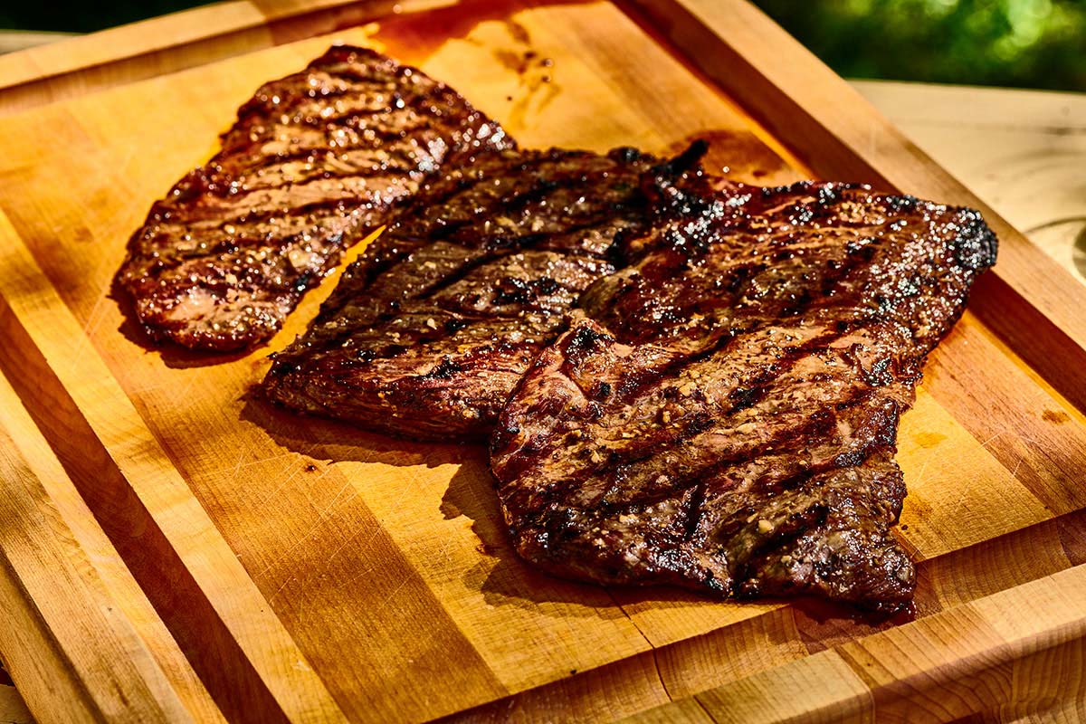 Grilled skirt steaks resting on wood cutting board.