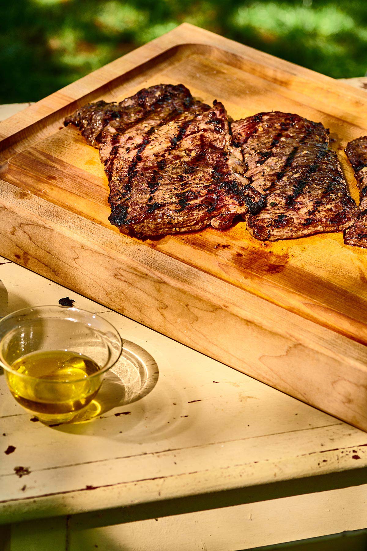 Grilled skirt steaks on a wooden cutting board.