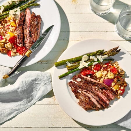 Balsamic-Marinated Skirt Steak on a plate with grilled asparagus and grilled vegetable couscous salad.