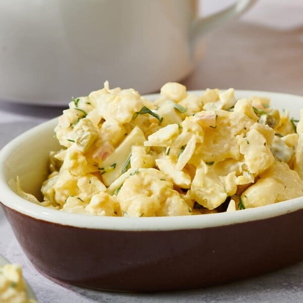 Brown dish with cauliflower potato salad on table.