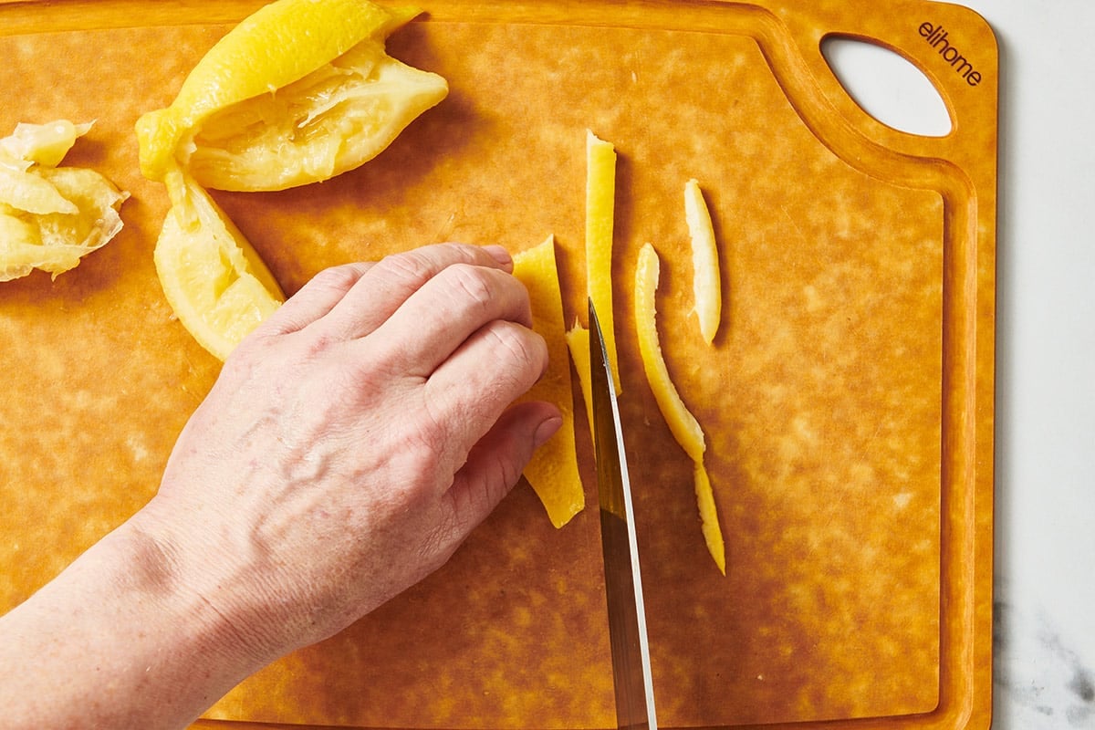 Slicing preserved lemons on wood cutting board.