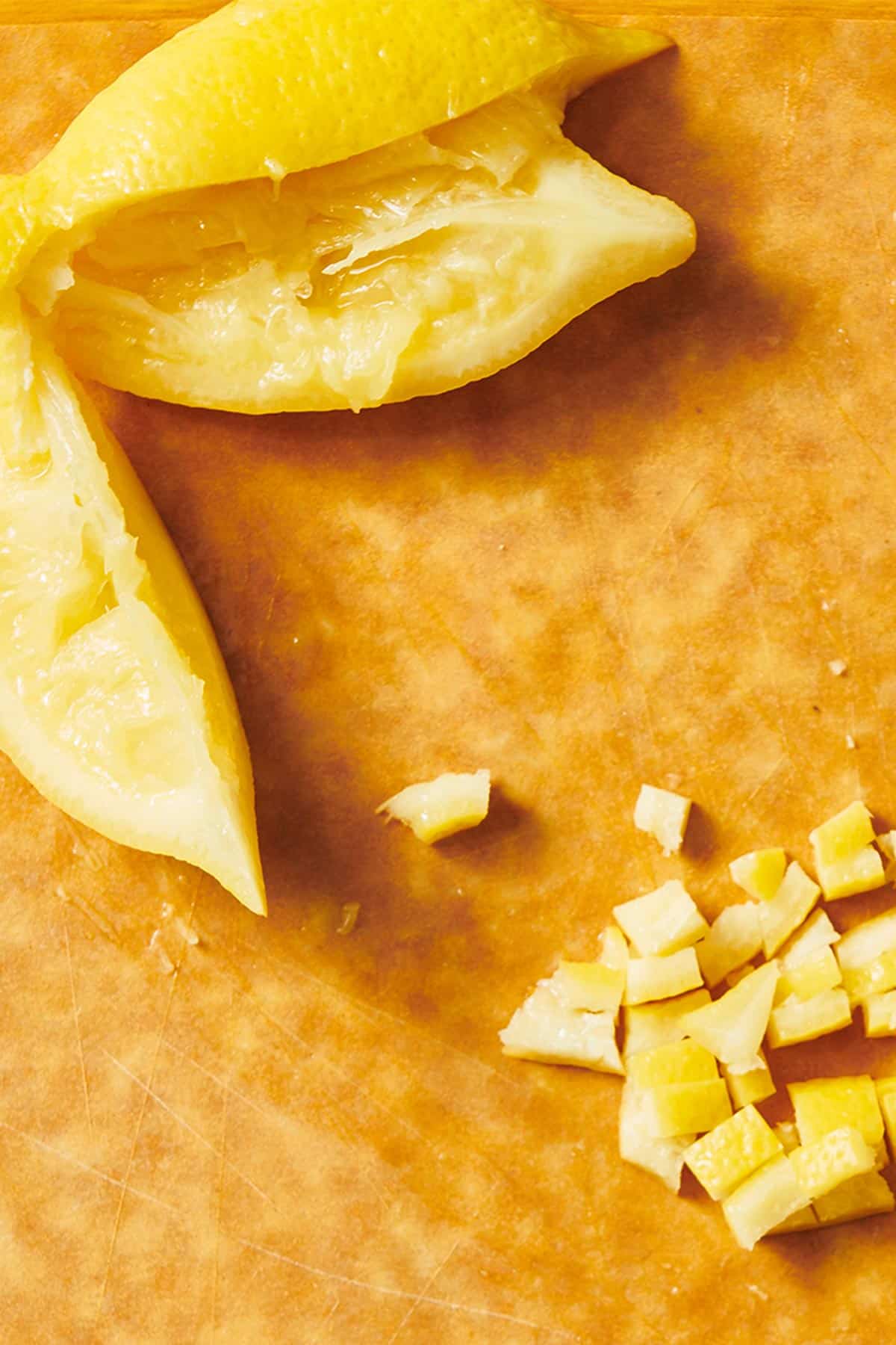 Diced and sliced homemade preserved lemons on wood cutting board.