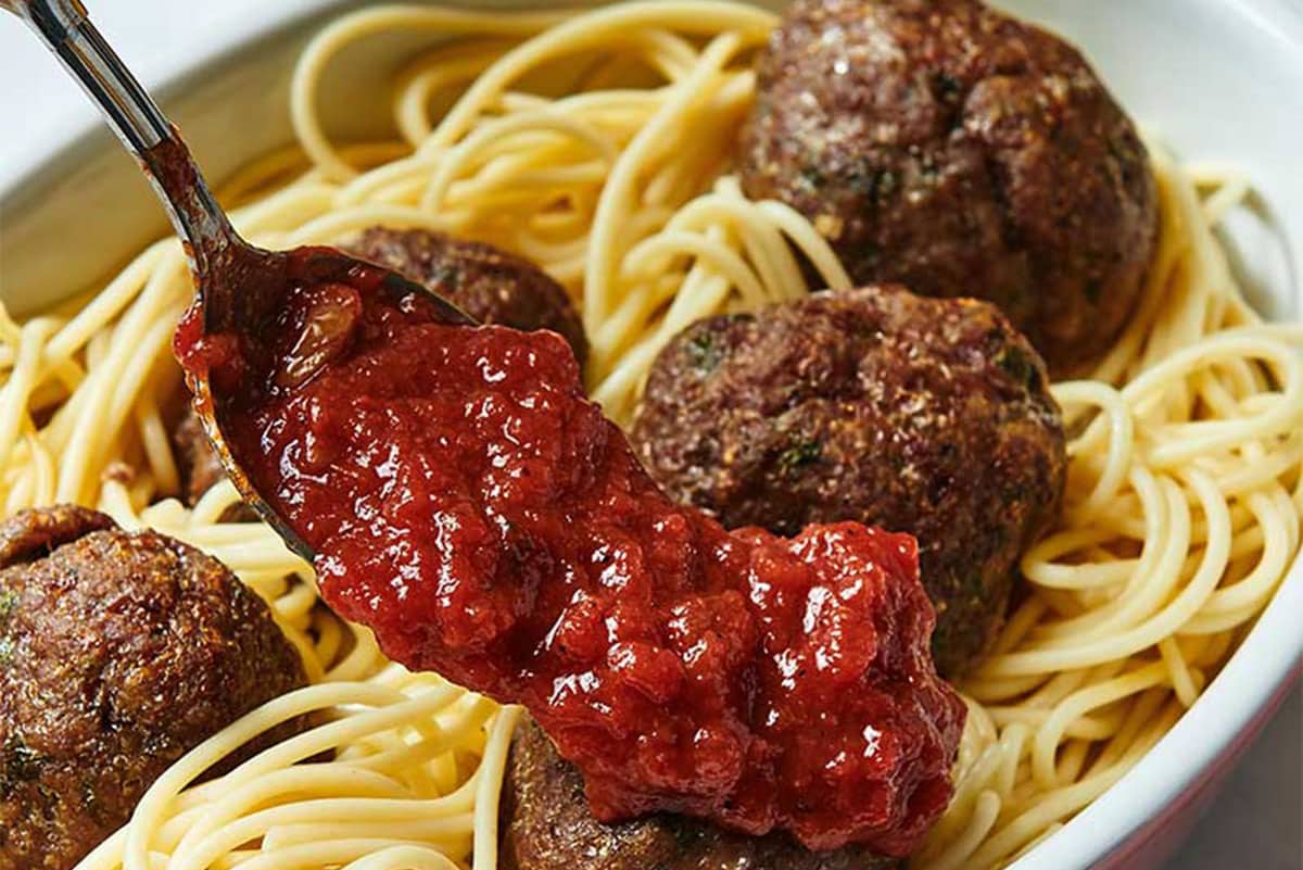 Spreading a platter of Jumbo Meatballs and spaghetti with marinara sauce.
