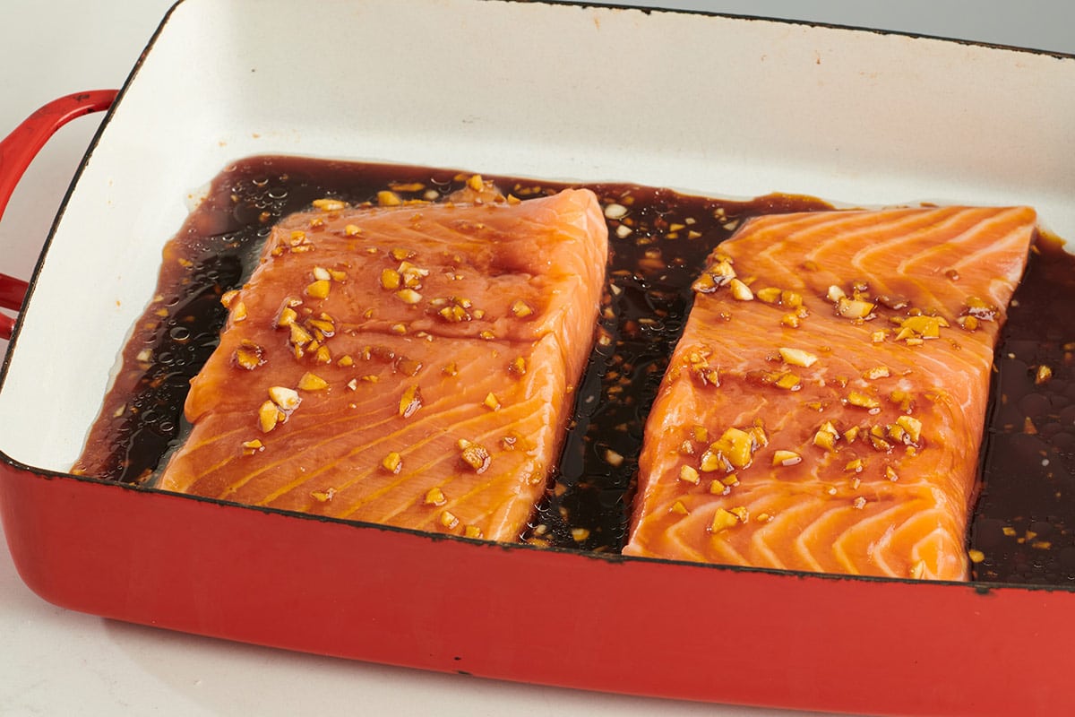 Salmon filets with teriyaki sauce in red roasting pan.