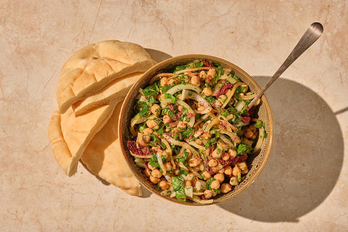 Turkish Chickpea Salad in brown bowl with pita bread and serving spoon.