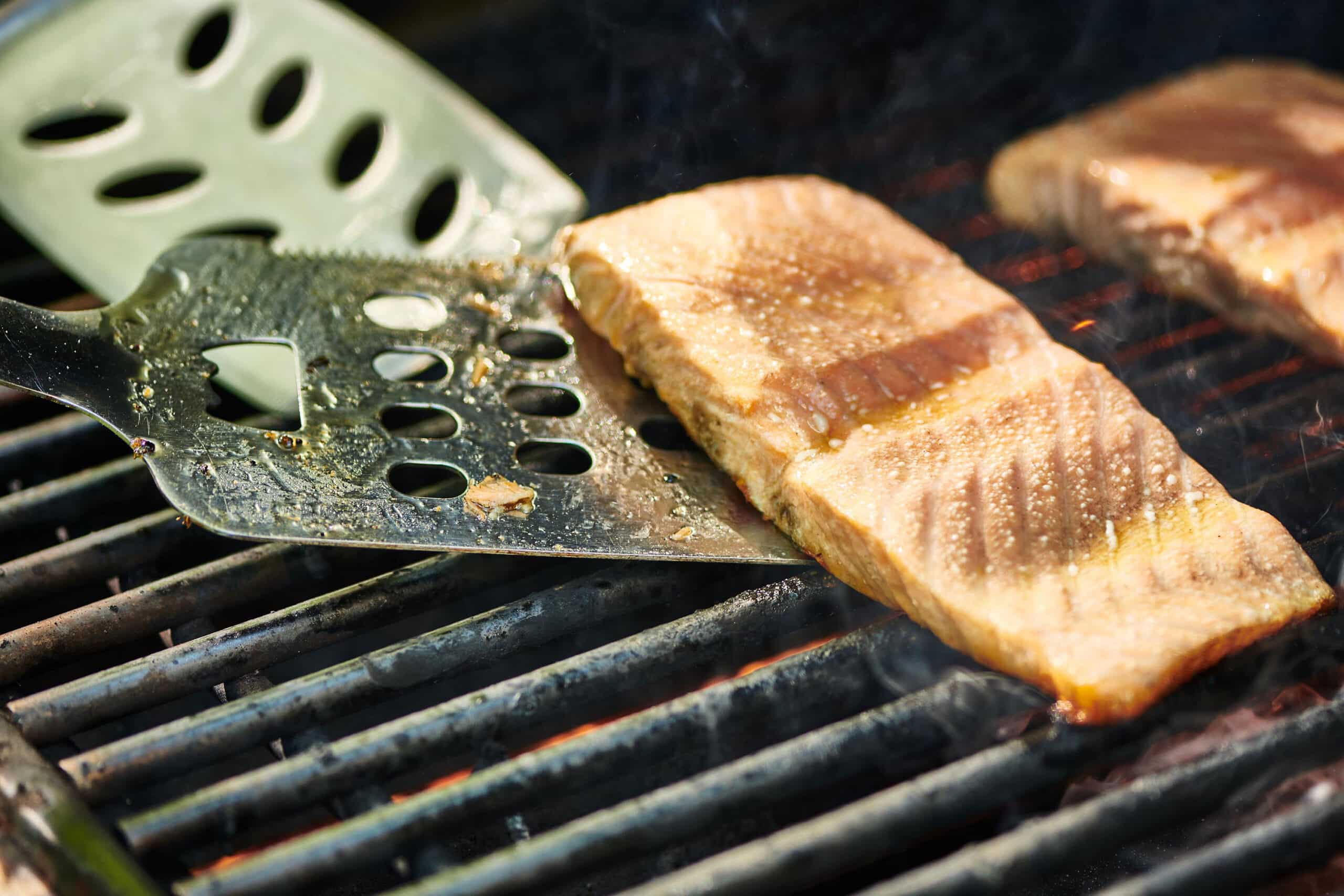Flipping salmon on grill with spatulas.