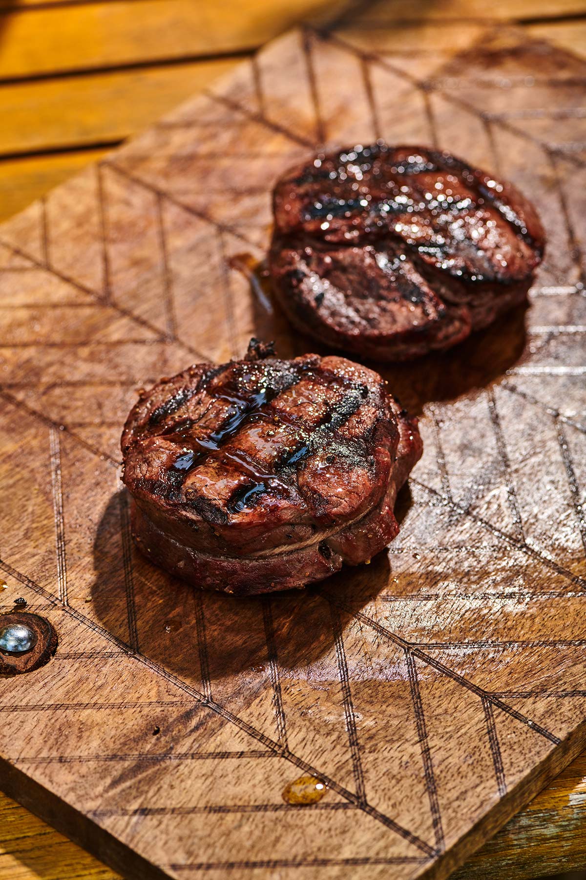 Cooked filet mignon steaks with cross-hatch grill marks on cutting board.