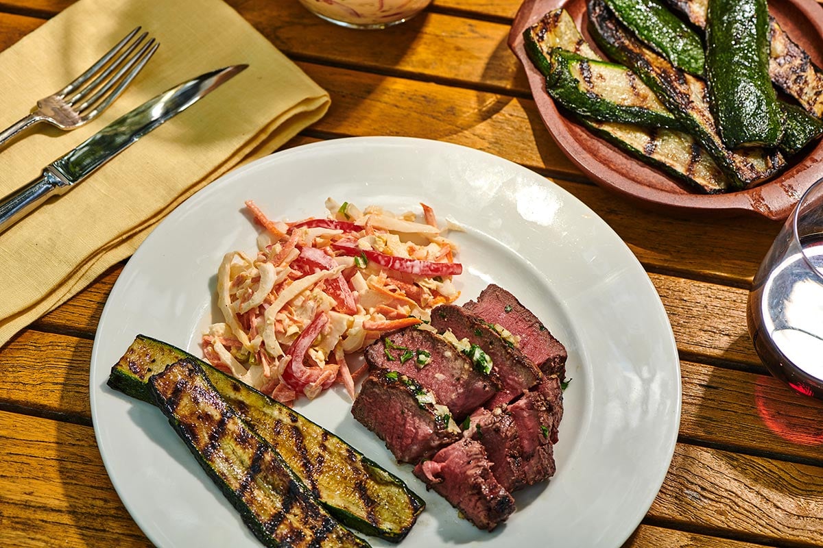 Grilled and slice filet mignon steak on plate with sides at cookout.