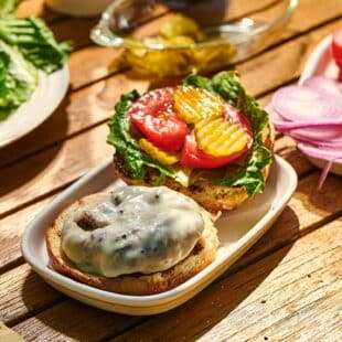 Grilled turkey burger with toppings on picnic table with side dishes.