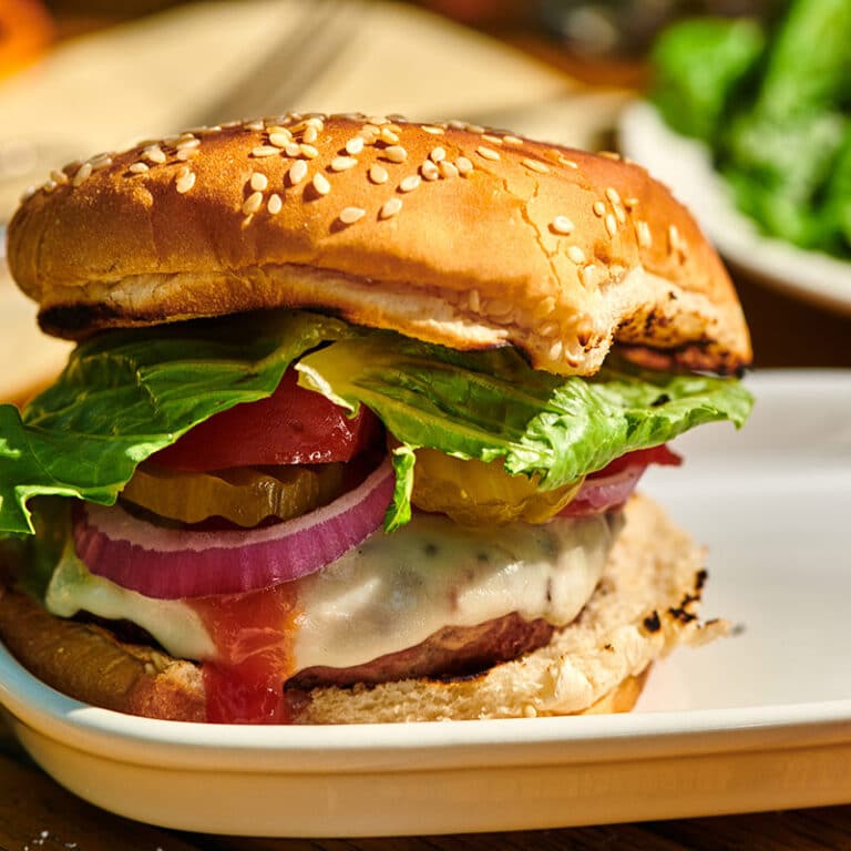 Grilled turkey burger with toppings and bun on white plate.