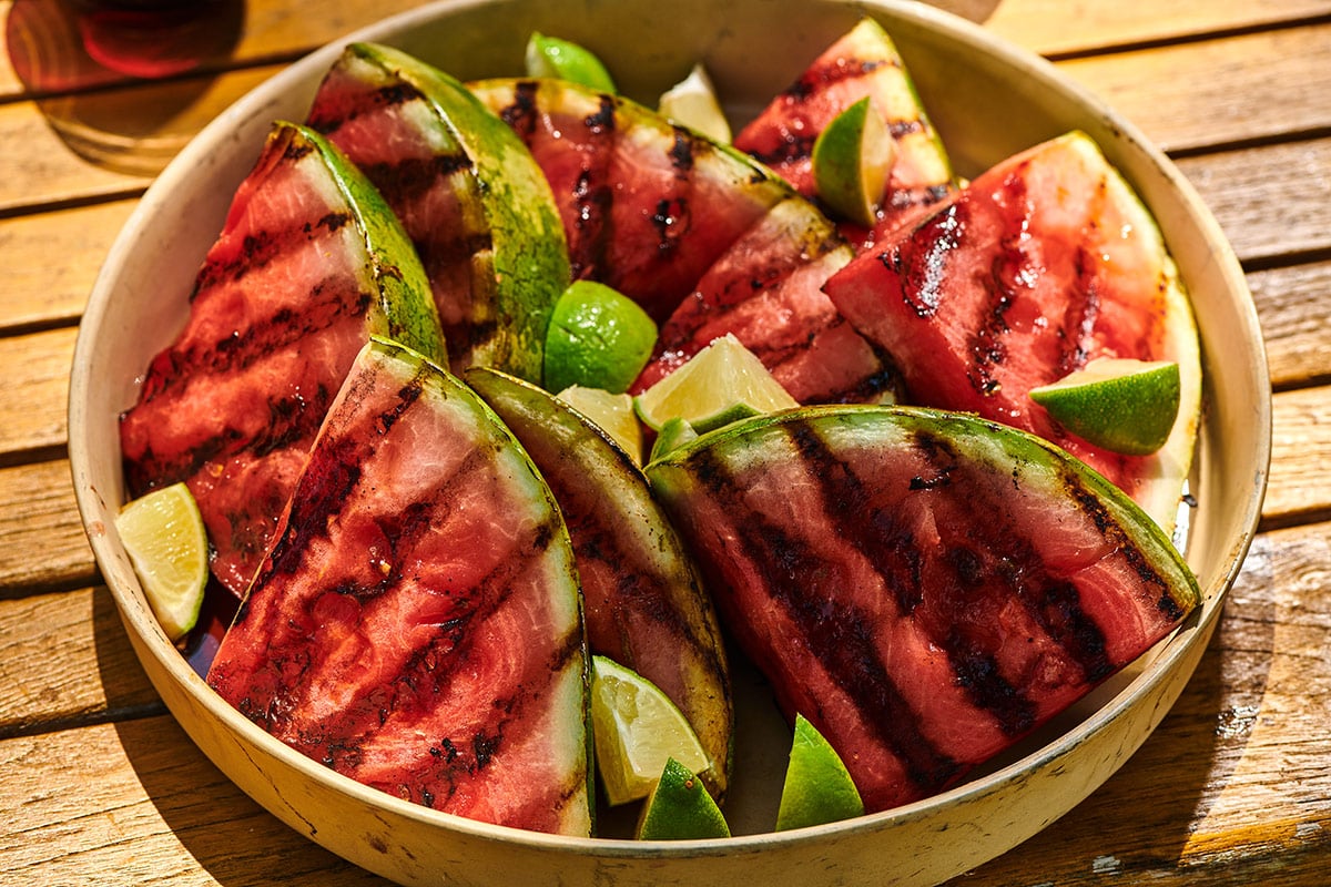 Freshly grilled watermelon on cookout serving platter with lime wedges.