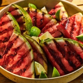 Slice of grilled watermelon on green plate during a cookout.