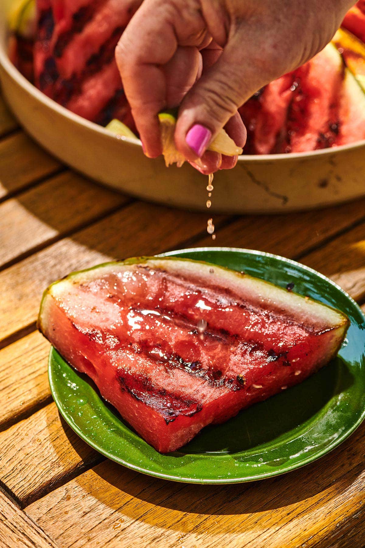Squeezing fresh lime juice over slice of grilled watermelon at cookout.
