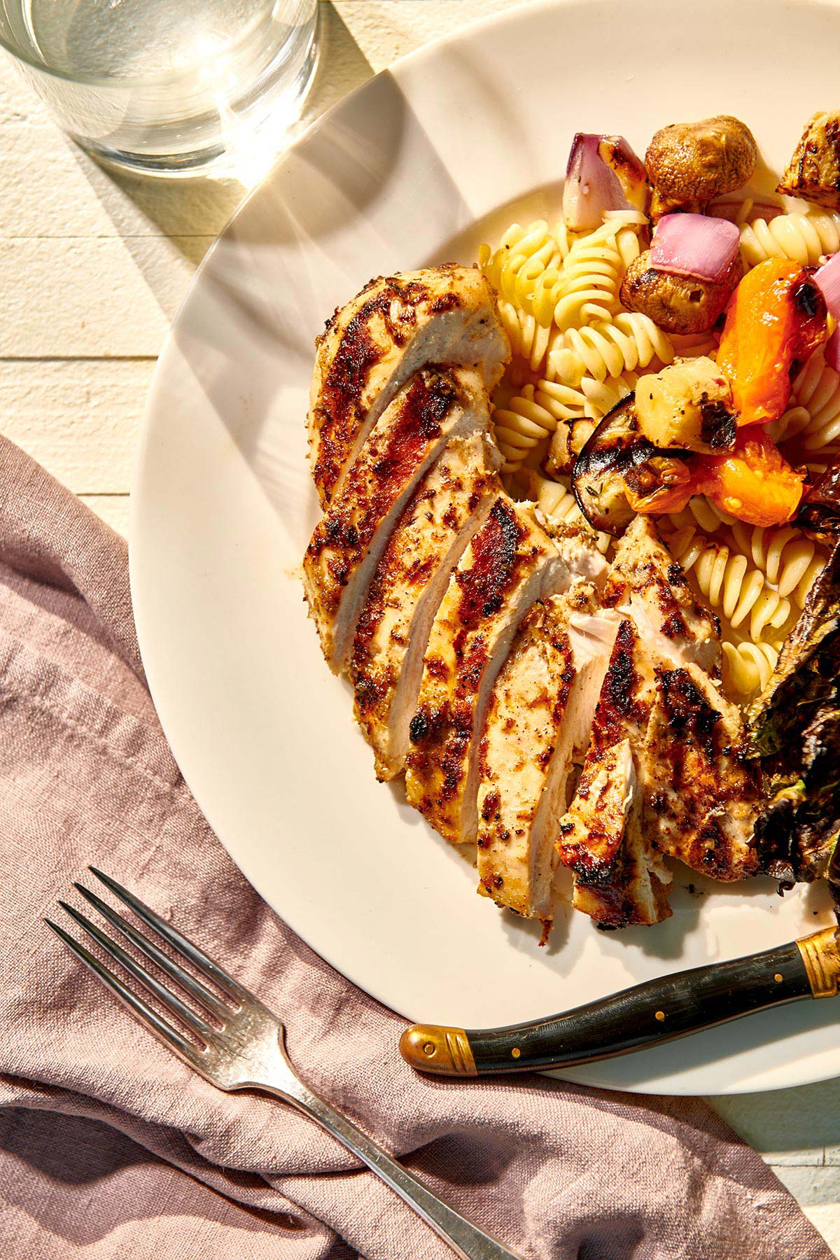 Grilled Jamaican jerk chicken breasts on plate with veggies.