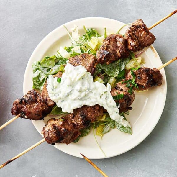 Greek Lamb Kabobs on plate with tzatziki dressing.