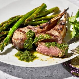 Rib lamb chops with pesto and asparagus on cookout plate.