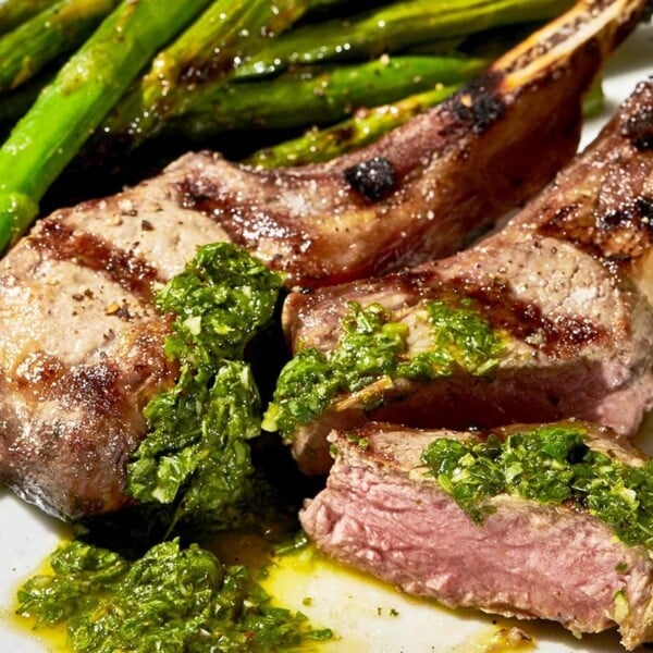 Grilled rib lamb chops smothered in mint-basil pesto on plate.