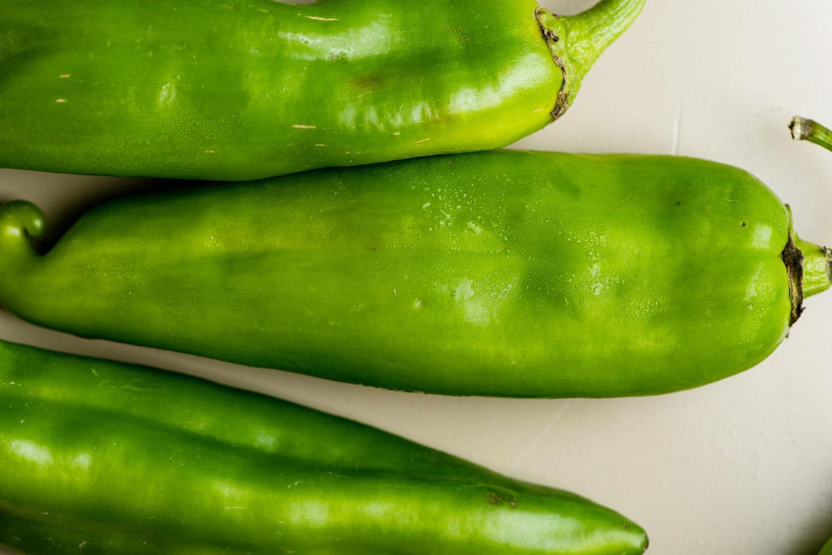 Three fresh Hatch chiles on table.