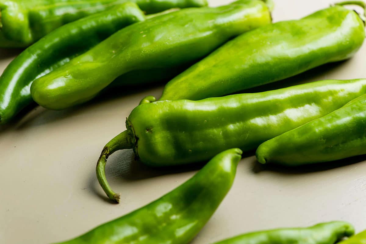 Fresh Hatch chiles laying out on white table.
