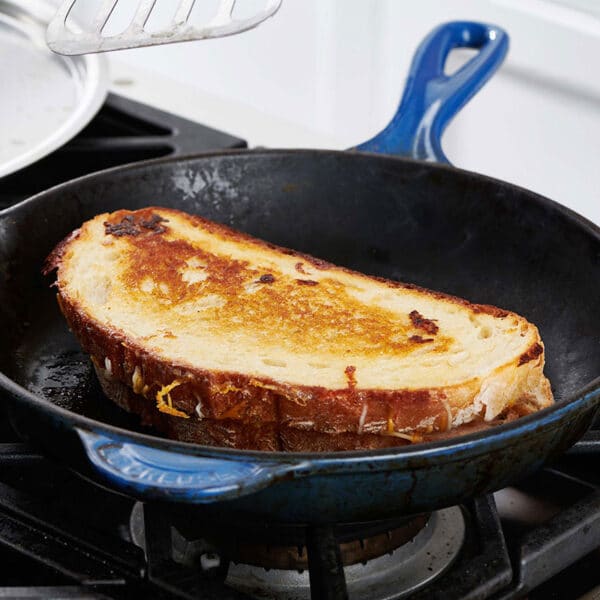 Grilled cheese sandwich in a blue skillet on the stove.