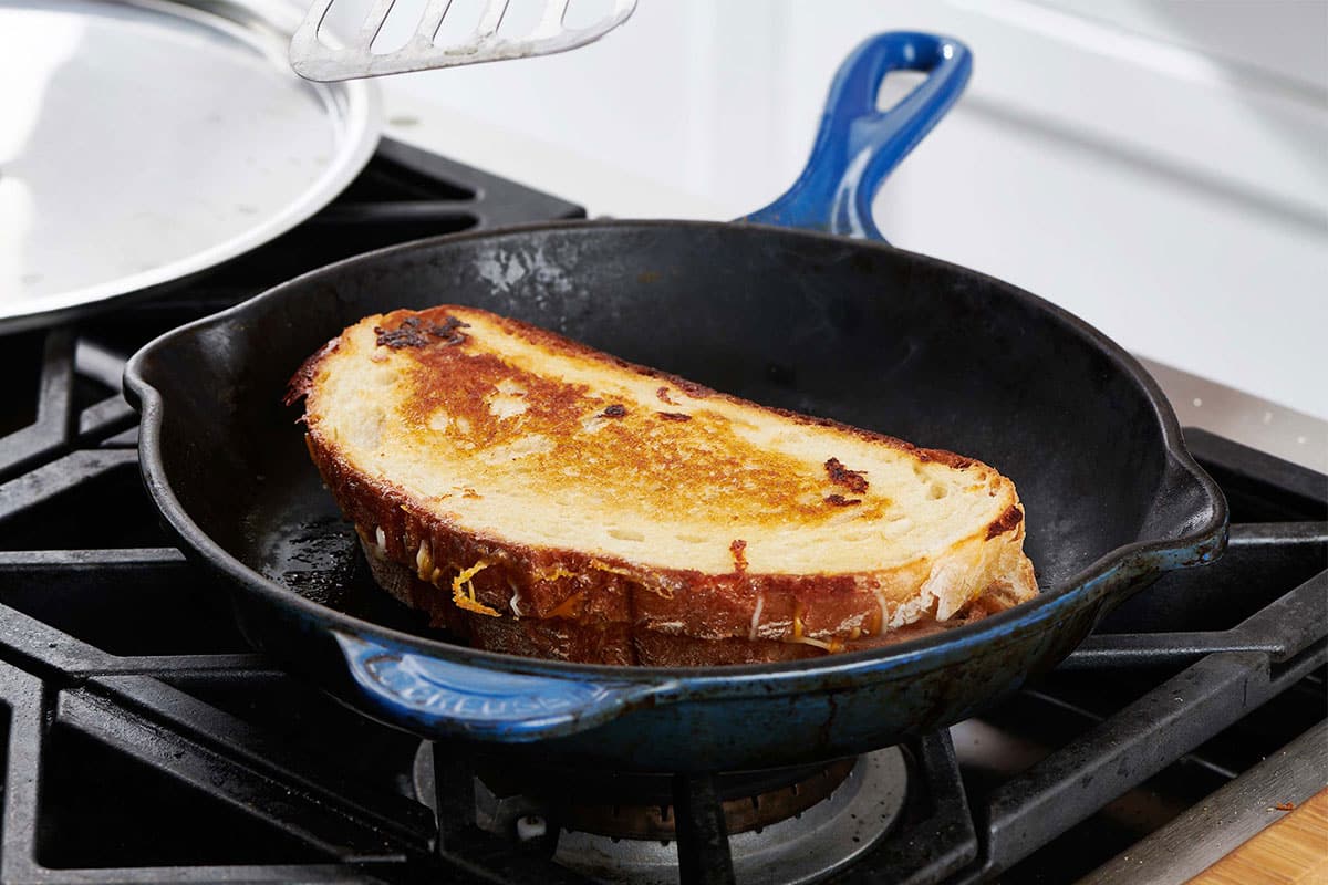 Grilled cheese sandwich in a blue skillet on the stove.