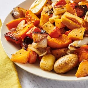 Roasted carrots, squash, parsnips, and other vegetables on white plate.