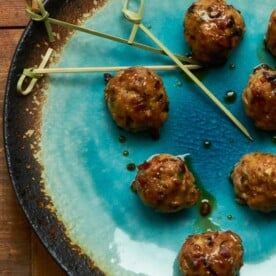 Japanese-style meatballs with ponzu glaze on blue and brown plate.
