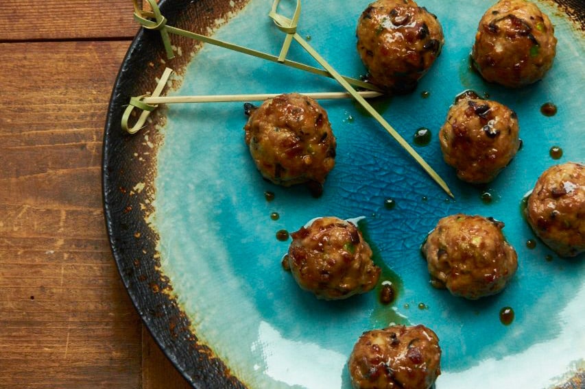Japanese-style meatballs with ponzu glaze on blue and brown plate.