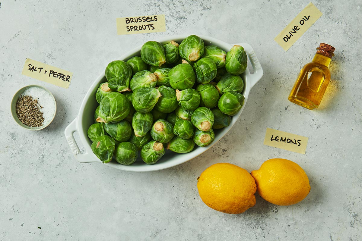 Brussels Sprouts, lemons, and other ingredients on marble.