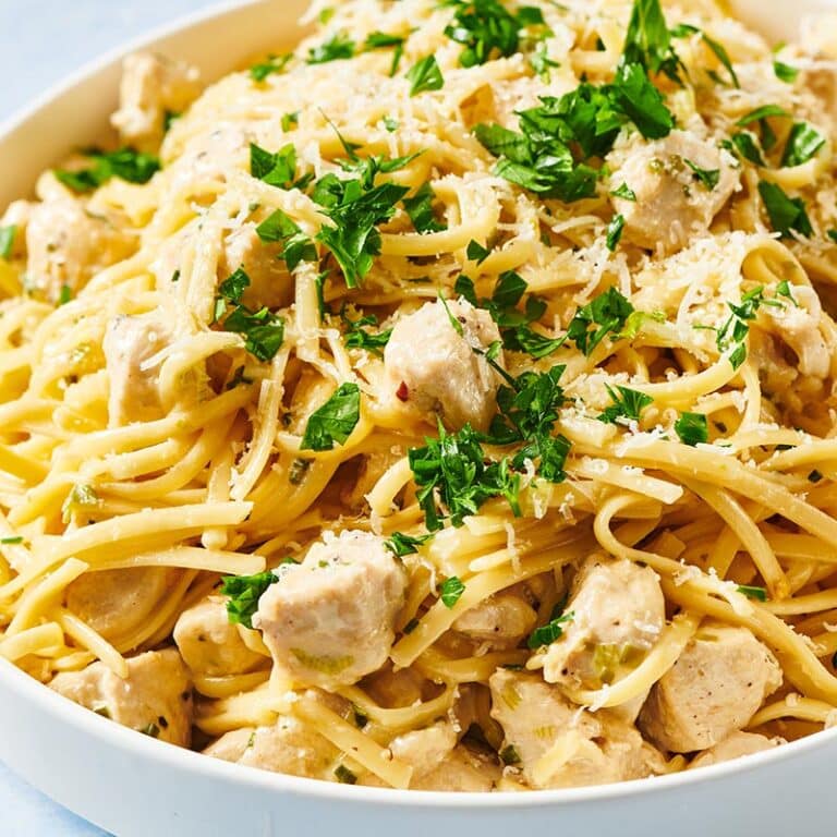 White bowl filled with chicken alfredo and parsley garnish.