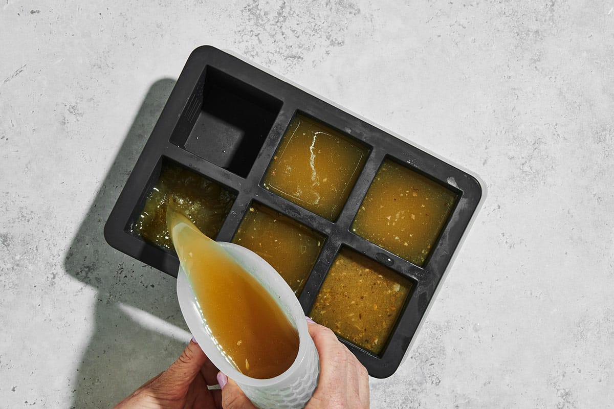 Pouring turkey stock into large ice cube tray.