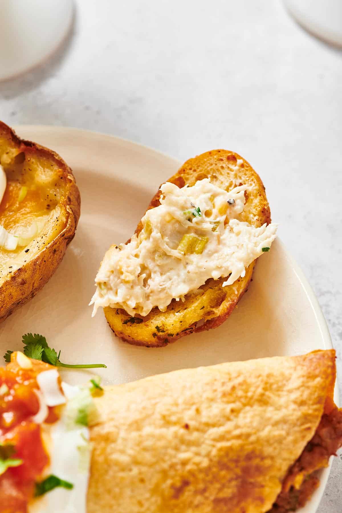 Crostini topped with hot crab dip on white plate.