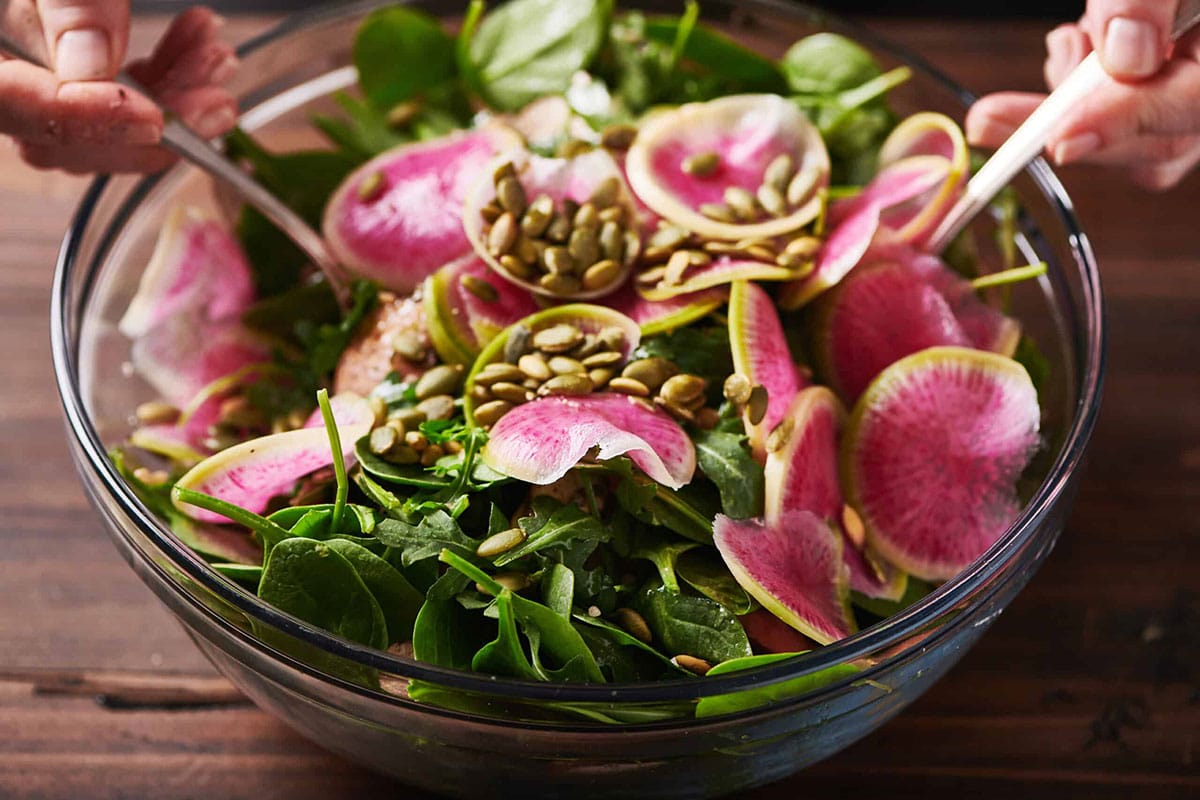 Fall Vegetable and Farro Salad topped with slices of watermelon radishes and pepitos.