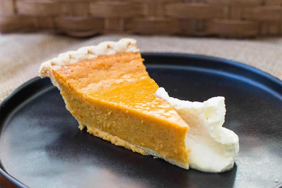 Slice of Sweet Potato Pie on a plate with whipped cream.