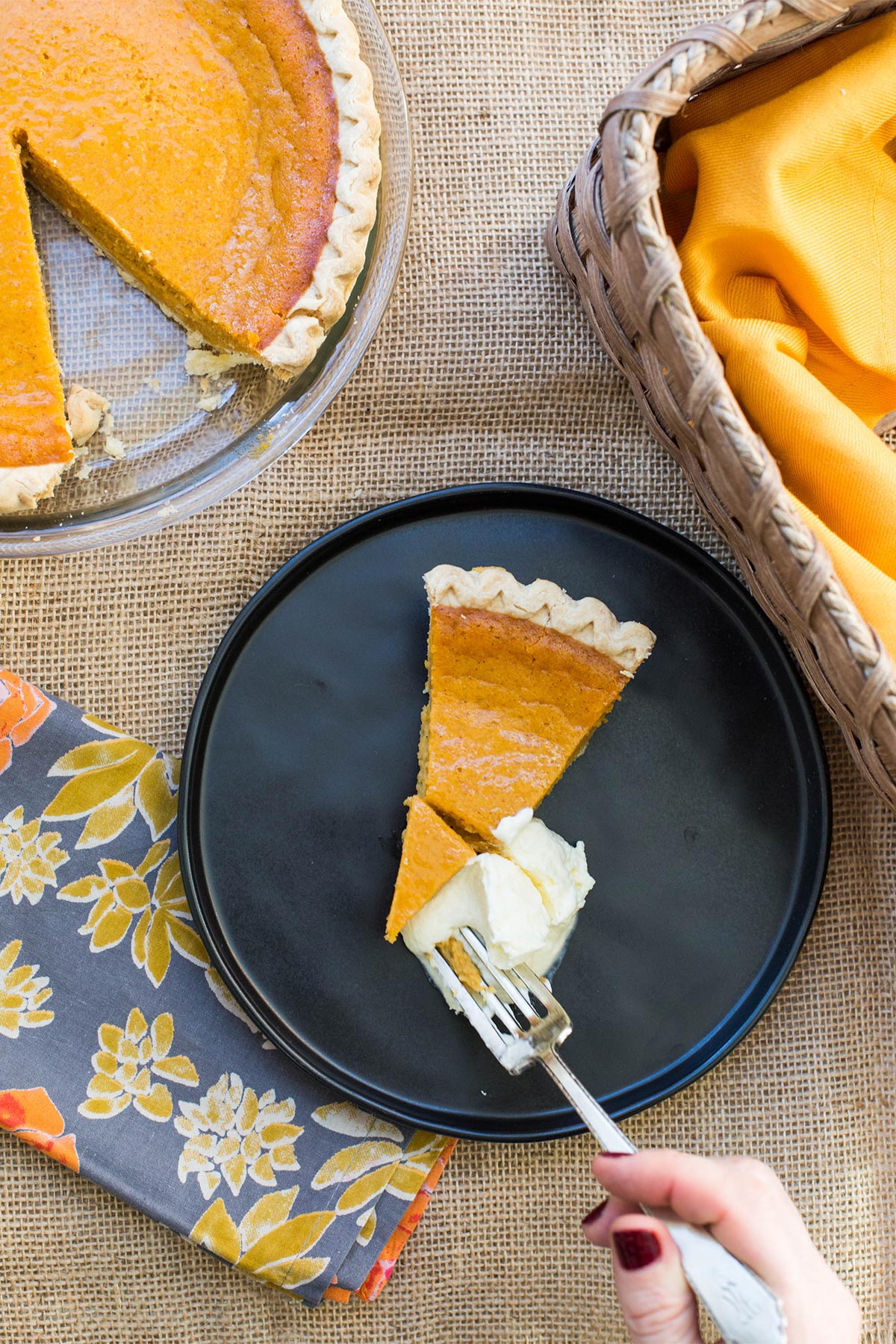 Woman about to scoop up a bite of sweet potato pie with whipped cream.