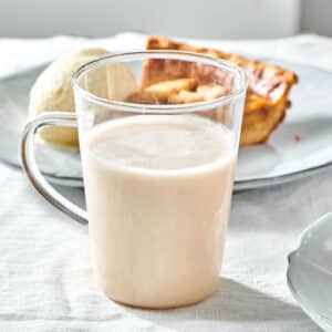 Glass with coquito drink on table with pumpkin pie.