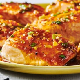 Ginger and lemongrass salmon filets piled on yellow plate.
