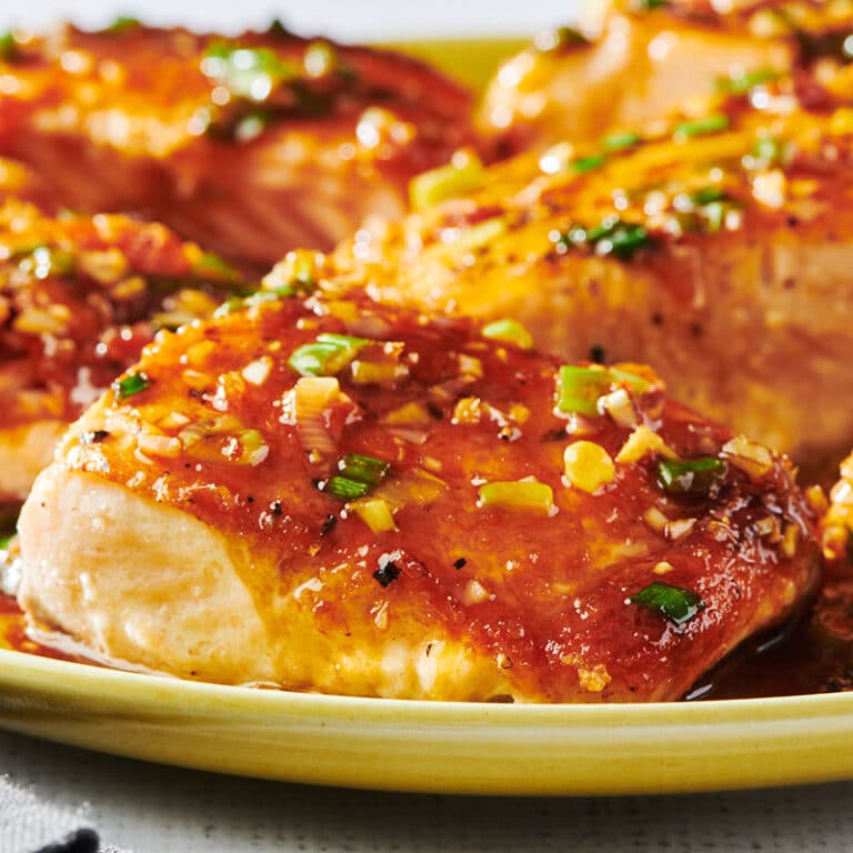 Ginger and lemongrass salmon filets piled on yellow plate.