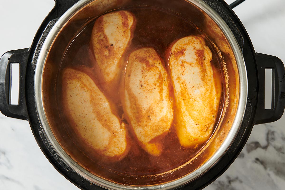 Chicken breasts in broth cooking in instant pot.