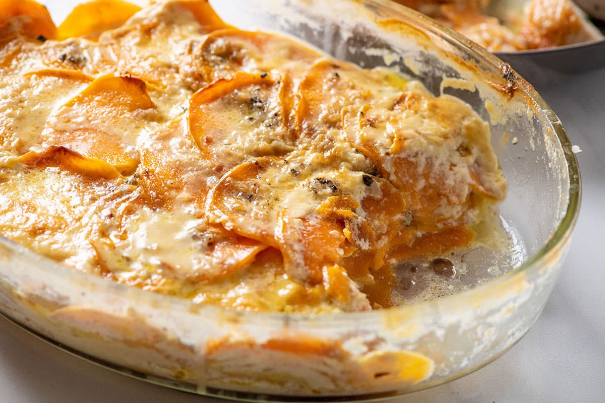 Scalloped sweet potatoes in glass baking dish.