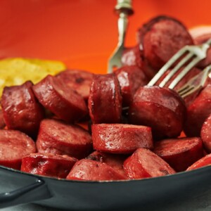 Air fried kielbasa in red bowl with mustard.