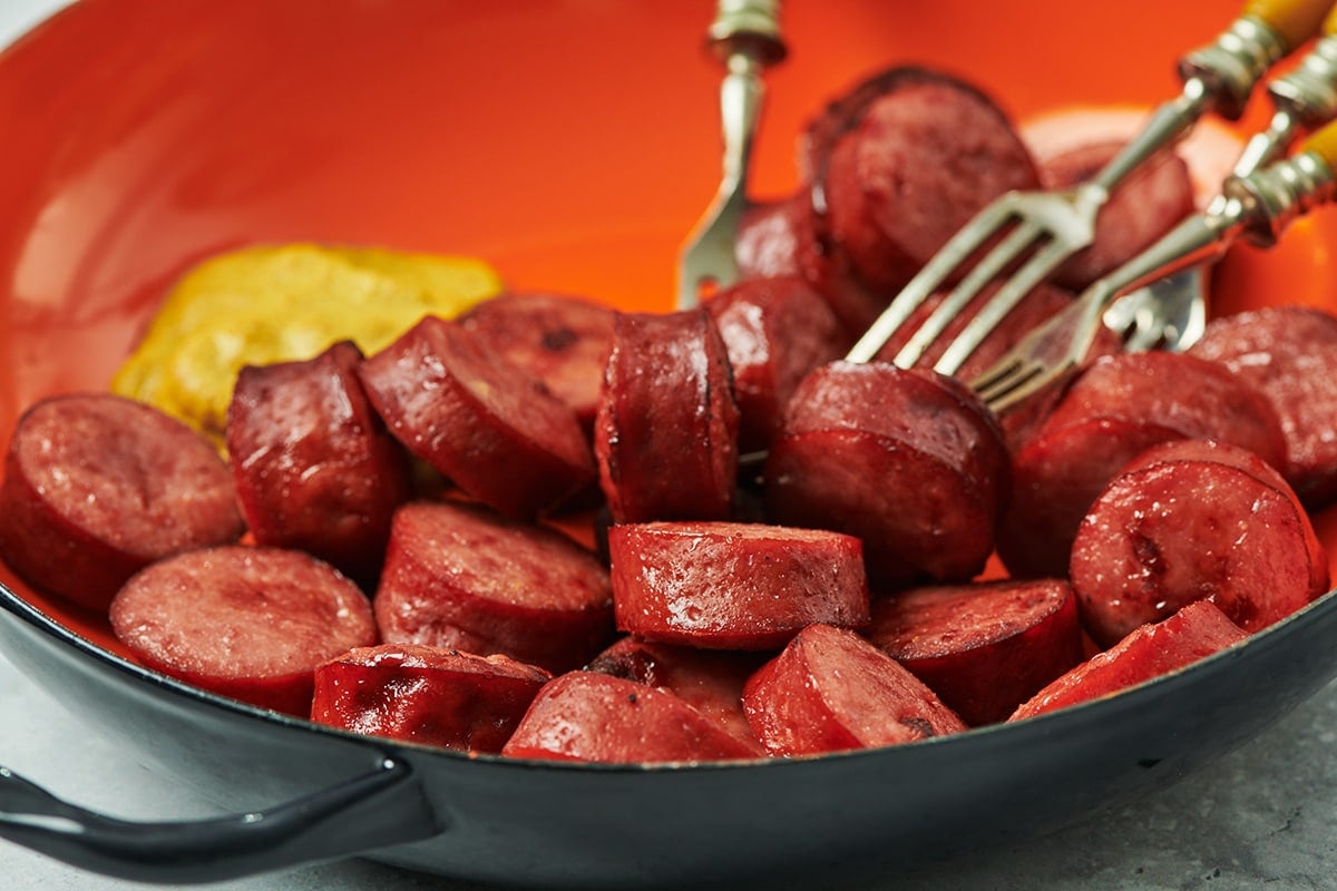 Air fried kielbasa in red bowl with mustard.