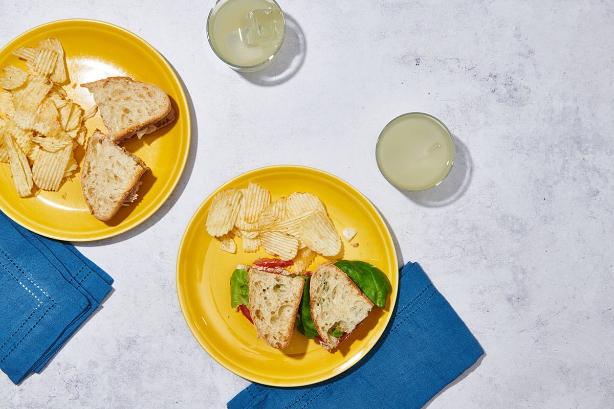 Tuna fish sandwiches on yellow plates with blue napkins.