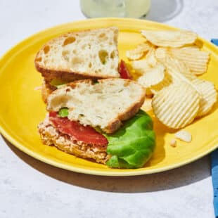 Tuna fish sandwich on yellow plate.