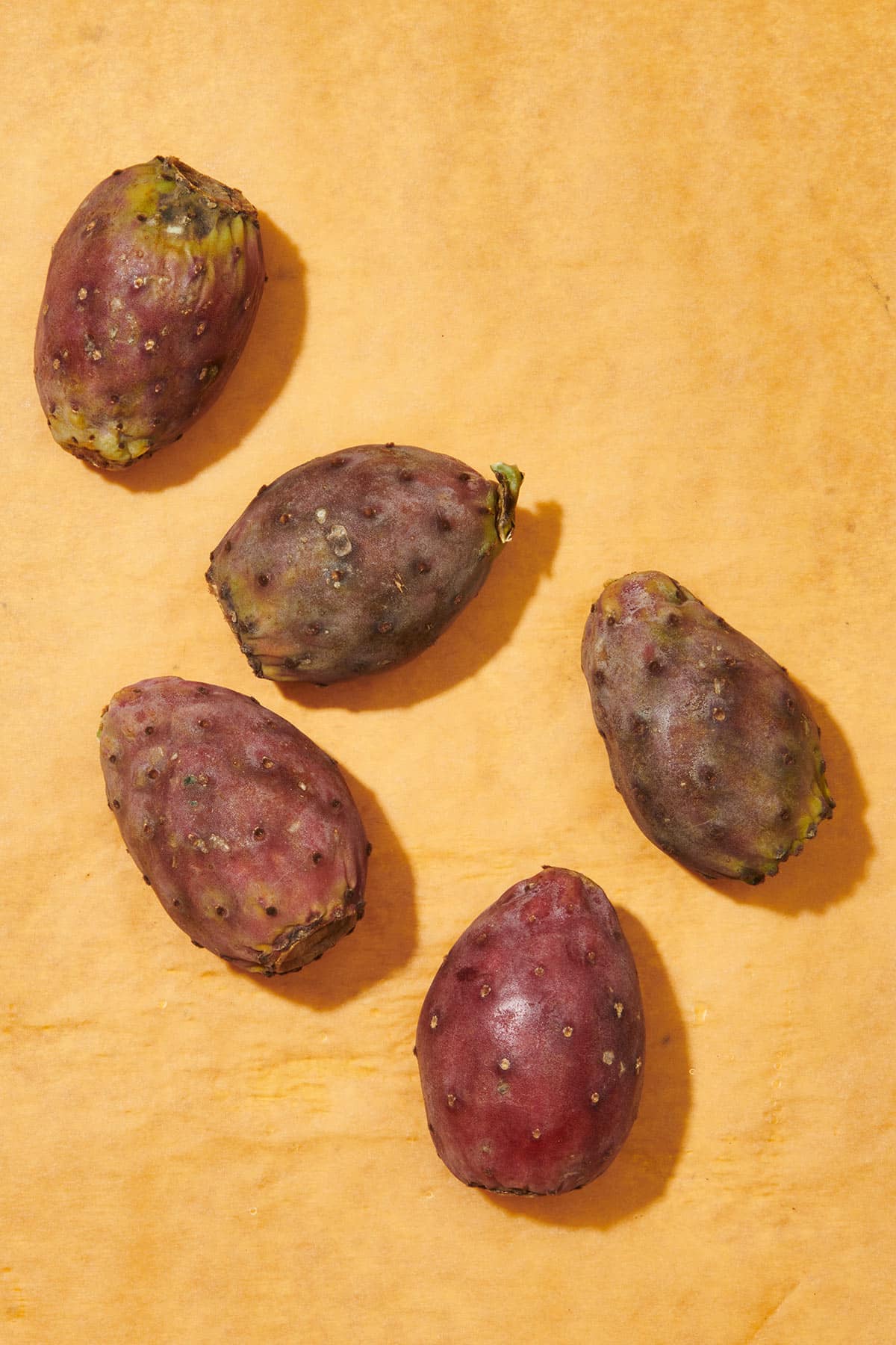 Five fresh prickly pears on cutting board.