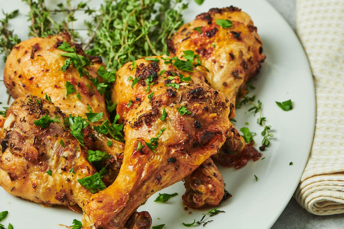 Baked crispy chicken drumsticks with herbs on white plate.