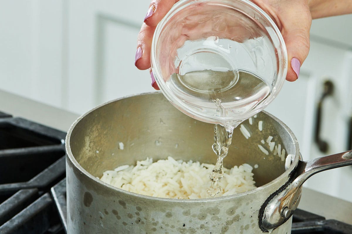 Pouring water into pot of leftover cooked rice.